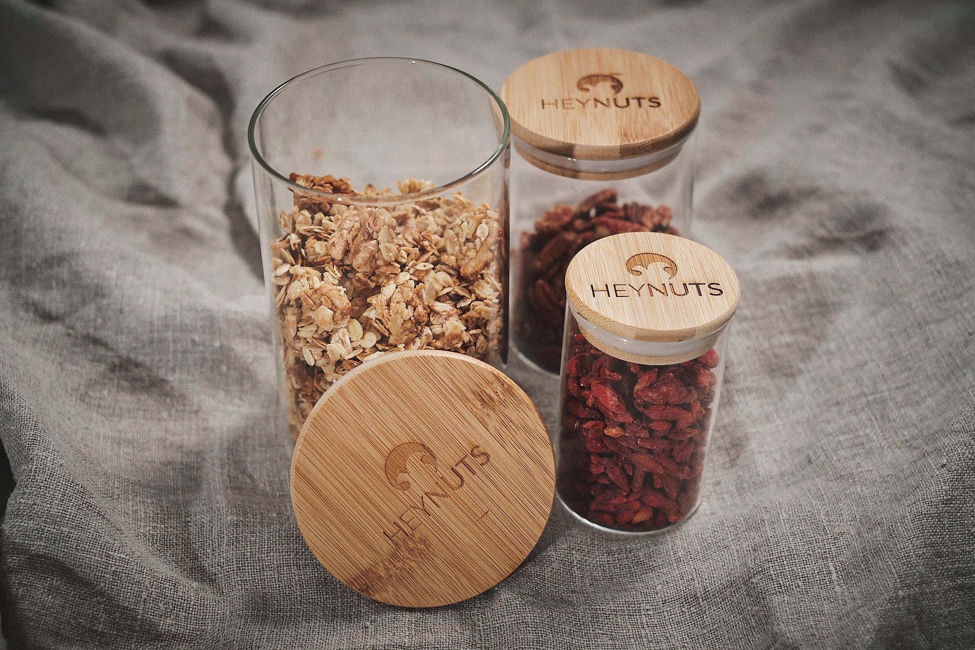 Vorratsglas mit Deckel, drei verschiedene Größen gefüllt und mit Heynuts logo auf dem Deckel